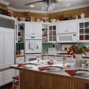 KITCHEN ; cherry theme, with white cabinets counter tops, natural wood stained wainscot , with view to oven fridge, cherry motif, red accents, green painted backsplash, checkered tile over stove,,, United States of America